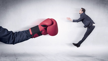 Huge Boxing Gloves punches innocent businessman concept
