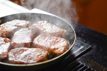 Fresh steaks are prepared in a pan with steam. Book of recipes. tasty food. menu. recipes. home and restaurant food