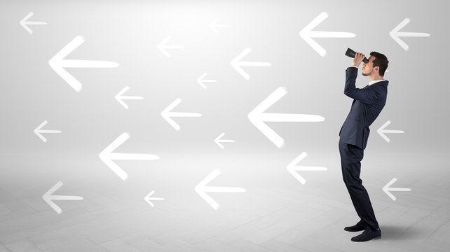 Young businessman standing and looking through binoculars with drawn arrows around
