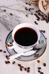 cup of coffee with beans on wooden background