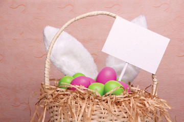 Bunny's ears behind a wicker basket full of colorful Easter eggs
