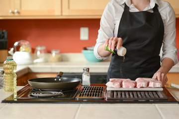 The chef prepares fresh pork steaks in the kitchen, salt the meat of the menu, home cooking. culinary recipes. restaurant menu.