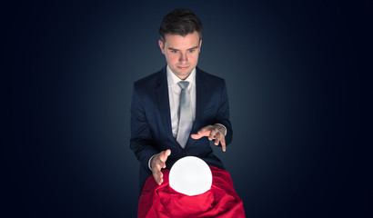 Handsome businessman with magic ball and copy space and dark background
