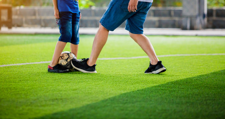 Kid soccer and dad are playing ball on at artificial turf, kid and dad are kick fighting to shoot...