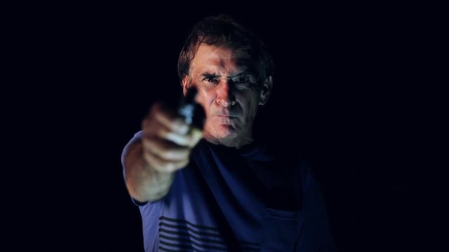Thug pointing a gun into a camera. Concept assault or murder.