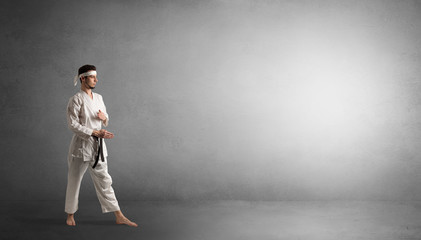 Small karate man fighting in an empty grey copy space