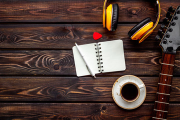 Professional d instruments with headphones, guitar, notebook and coffee on wooden background top view mockup