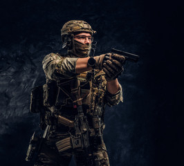 The elite unit, special forces soldier in camouflage uniform holding a pistol and looking sideways