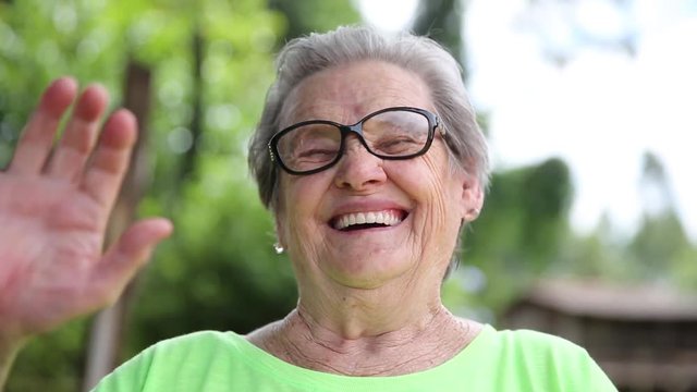 Elderly waving with hands. Greet or say goodbye. Looking at the camera.