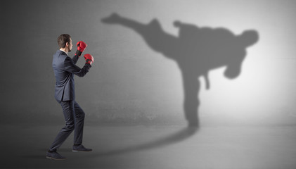 Businessman fighting with his strong karate man shadow
