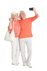Portrait of happy senior couple taking selfie on white background