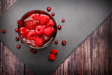 Fresh, raspberry and cranberriy iced cocktail on wooden background. Top view. Fruity cocktail drink decorated with frozen cranberries. Copy space.
