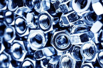 Metal nuts stack texture. Blue industrial hardware store background.