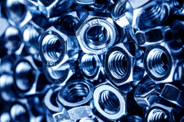 Metal nuts stack texture. Blue industrial hardware store background.
