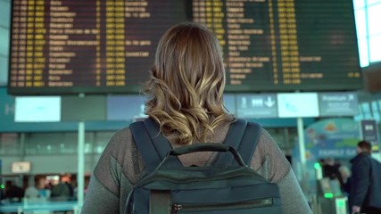 Woman traveler looking at information board in airport