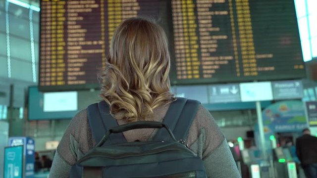 Woman traveler looking at information board in airport