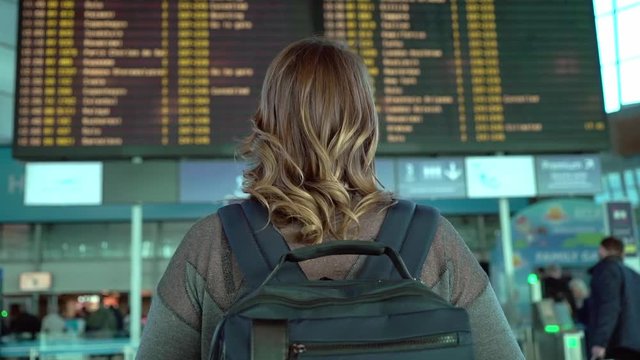 Woman traveler looking at information board in airport