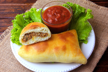 meat esfiha (sfiha) of Arab origin traditionally adapted for the Brazilian cuisine on plate on rustic wooden table