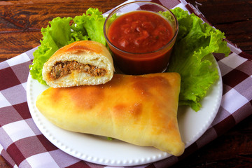 meat esfiha (sfiha) of Arab origin traditionally adapted for the Brazilian cuisine on plate on rustic wooden table