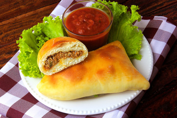meat esfiha (sfiha) of Arab origin traditionally adapted for the Brazilian cuisine on plate on rustic wooden table