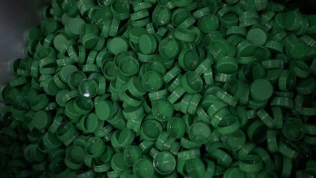 Green plastic bottle caps. Plastic waste. Packaging equipment at dairy factory