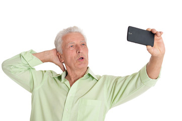 Portrait of confident senior man taking selfie on white background