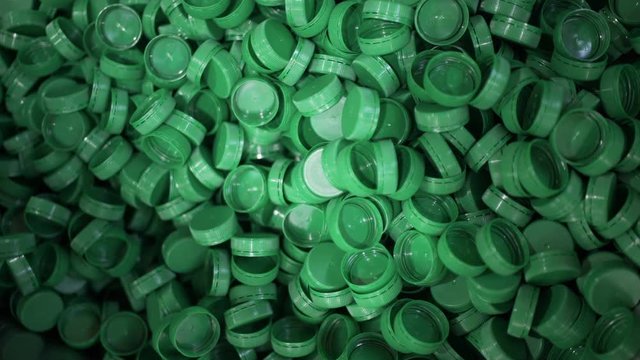 Green plastic bottle caps. Plastic waste. Packaging equipment at dairy factory