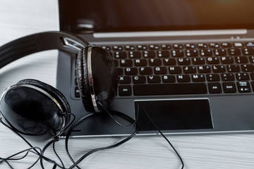 Black music headphone with laptop computer on wooden table top view