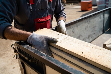 Close up on the worker holding building material planks loading at the warehouse for the construction site