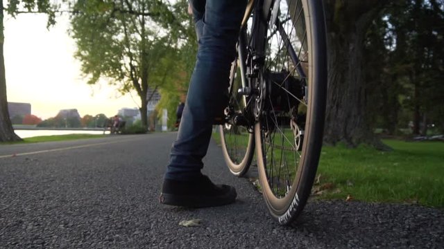 Following man riding bicycle in slowmo at sunset.