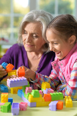 Portrait of grandmother playing with her little granddaughter at home