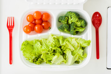 top view of tasty organic vegetables near plastic fork and spoon