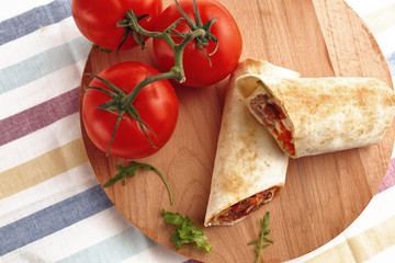 Shawarma in pita and natural organic tomatoes with greens, on a wooden background