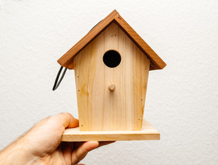 Obraz na płótnie Canvas Adult male hands holding birds nesting birdhouse house ready to be installed in the garden on a tree