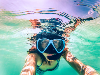 Naklejka premium woman taking an underwater selfie while snorkeling in crystal clear tropical water