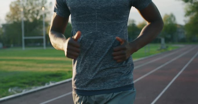 Slow motion of young african male athlete is running on race track in athletics stadium.