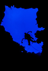 A silhouette shot of a scuba diver with an underwater camera in his hand descending into the abyss. The image is framed by a naturally occuring hole in the reef