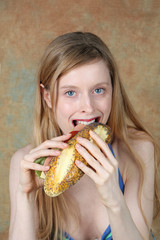 Young blonde woman eating a sandwich