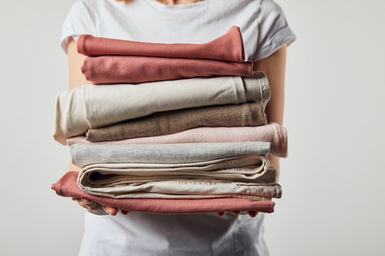 Cropped view of woman holding folded ironed clothes isolated on grey