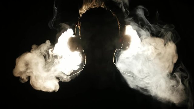 Silhouette of young boy smoking electronic cigarette in the darkness. 