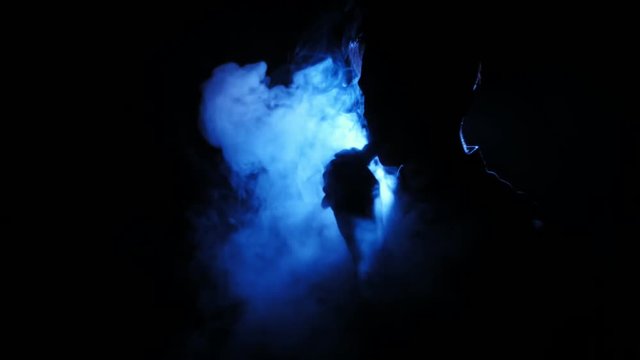 Silhouette of vaping man in the darkness. Boy blowing O's with vapor from e-cigarette. Vape tricks