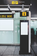 A vertical view of the template of an electronic contemporary information desk with intercom and camera indoors of a modern airport terminal with a LCD screen mock-up as a departure board on the wall