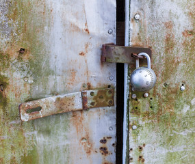 New steel lock mounted on rickety, derelict metal shed door.