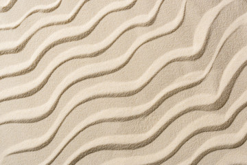 Fototapeta na wymiar top view of beige sandy backdrop with smooth waves