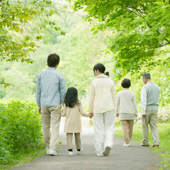 新緑の中で手をつなぐ3世代家族の後姿