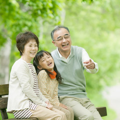 ベンチに座り微笑む祖父母と孫