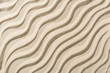 Fototapeta na wymiar top view of beige sandy backdrop with smooth waves