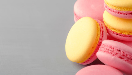 Pink yellow macaroons cakes on gray blue table background, place for text, trendy minimalism style, selective focus