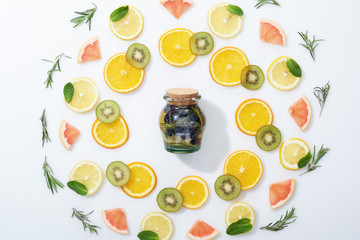 flat lay with sliced kiwi, oranges, lemons, grapefruits, mint, rosemary and detox drink in jar