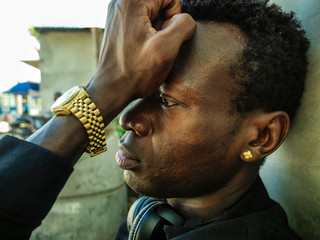 urban lifestyle portrait of young sad and depressed black African American man sitting outdoors on...